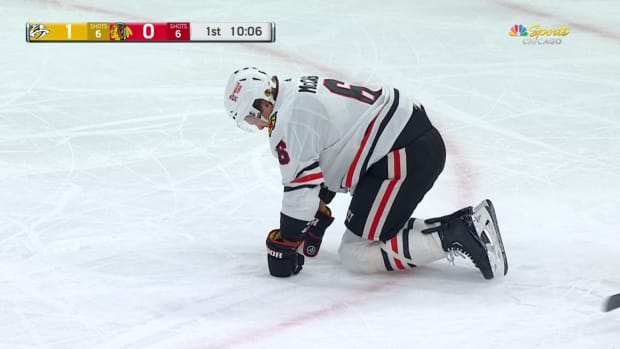 Chicago Blackhawks defenseman Jake McCabe falls to the ice in pain after taking a stick to the face against the Nashville Predators on Wednesday, Dec. 21, 2022