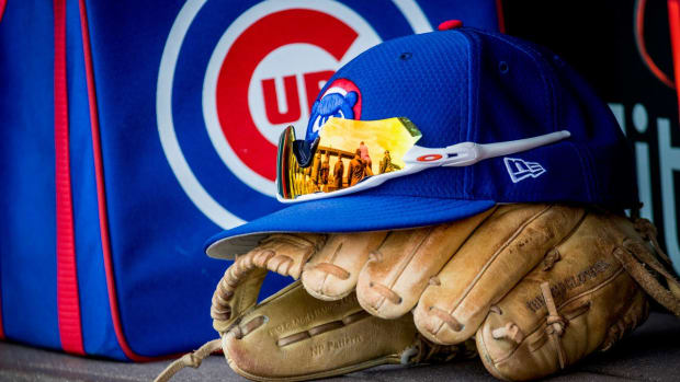 Sunglasses rest upon a Chicago Cubs Spring Training hat, which sits on top of a glove with a Cubs duffle bag in the background