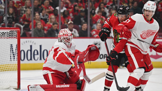 Oct 1, 2022; Chicago, Illinois, USA; Detroit Red Wings goaltender Alex Nedeljkovic (39) makes a save on a shot as Chicago Blackhawks forward Brett Seney (62) and defenseman Eemil Viro (51) battle for position in the first period at the United Center.