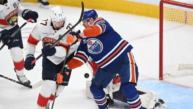 Jun 6, 2025; Edmonton, Alberta, CAN; Edmonton Oilers right wing Corey Perry (90) and Florida Panthers defenseman Niko Mikkola (77) attempt to get the puck during the second period in game two of the 2025 Stanley Cup Final at Rogers Place.