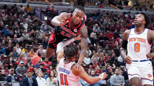 Apr 5, 2024; Chicago, Illinois, USA; Chicago Bulls guard Ayo Dosunmu (12) charges into New York Knicks guard Jalen Brunson (11) during the first quarter at United Center.