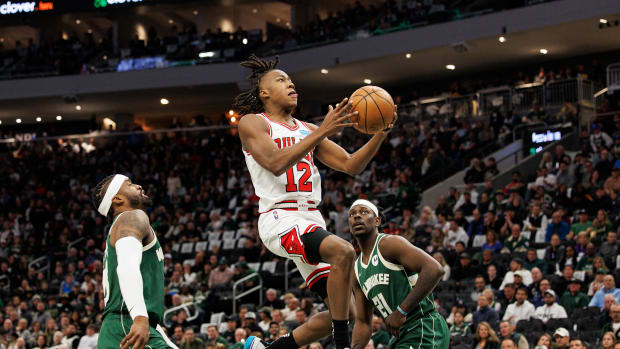 Apr 27, 2022; Milwaukee, Wisconsin, USA; Chicago Bulls guard Ayo Dosunmu (12) drives for a layup between Milwaukee Bucks guard Wesley Matthews (23) and guard Jrue Holiday (21) during the third quarter during game five of the first round for the 2022 NBA playoffs at Fiserv Forum.