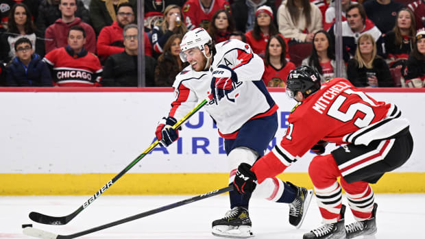 Dec 13, 2022; Chicago, Illinois, USA; Washington Capitals forward T.J. Oshie (77) puts a shot on goal past the defense of Chicago Blackhawks defenseman Ian Mitchell (51) in the second period at United Center.