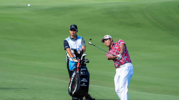January 5, 2023; Maui, Hawaii, USA; Hideki Matsuyama (right) hits his chip shot in front of caddie Shota Hayafuji (left) on the third hole during the first round of the Sentry Tournament of Champions golf tournament at Kapalua Resort - The Plantation Course.