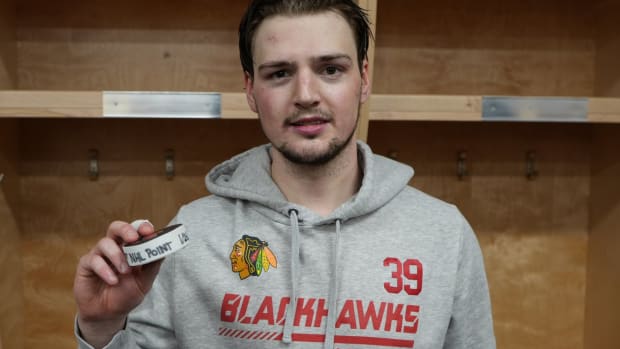 Chicago Blackhawks forward Luke Philp poses with the puck that was used when he scored his first NHL point