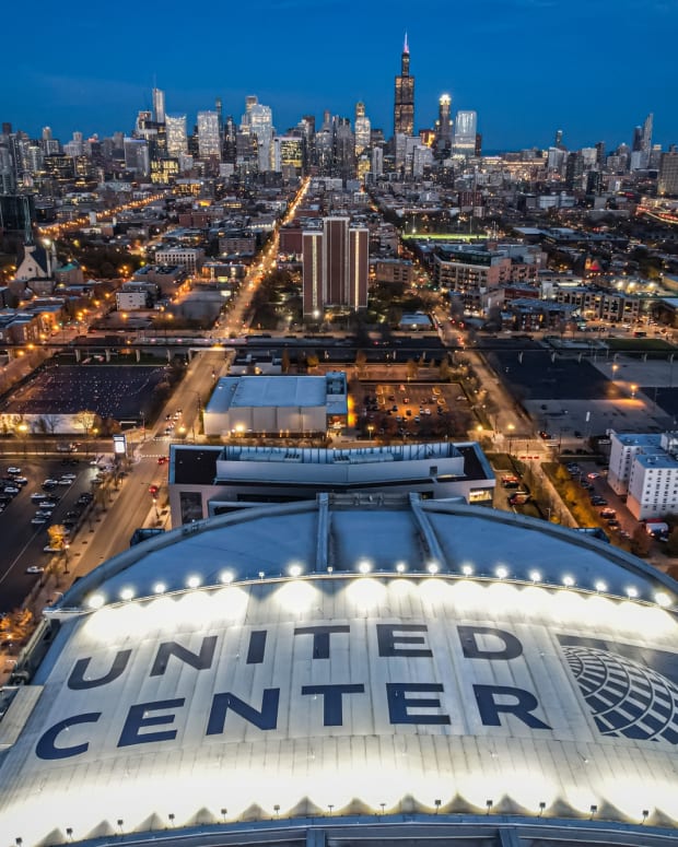 An aerial photo of the United Center with the Chicago skyline in the background