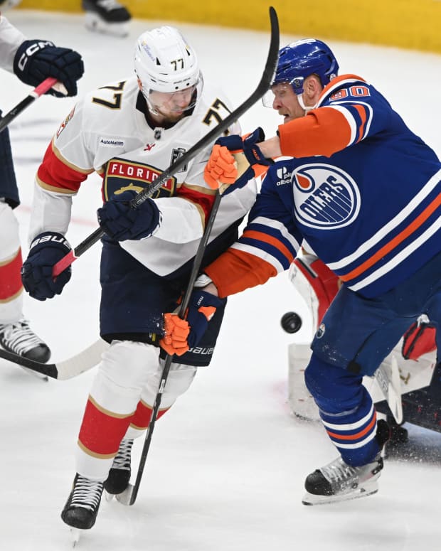 Jun 6, 2025; Edmonton, Alberta, CAN; Edmonton Oilers right wing Corey Perry (90) and Florida Panthers defenseman Niko Mikkola (77) attempt to get the puck during the second period in game two of the 2025 Stanley Cup Final at Rogers Place.